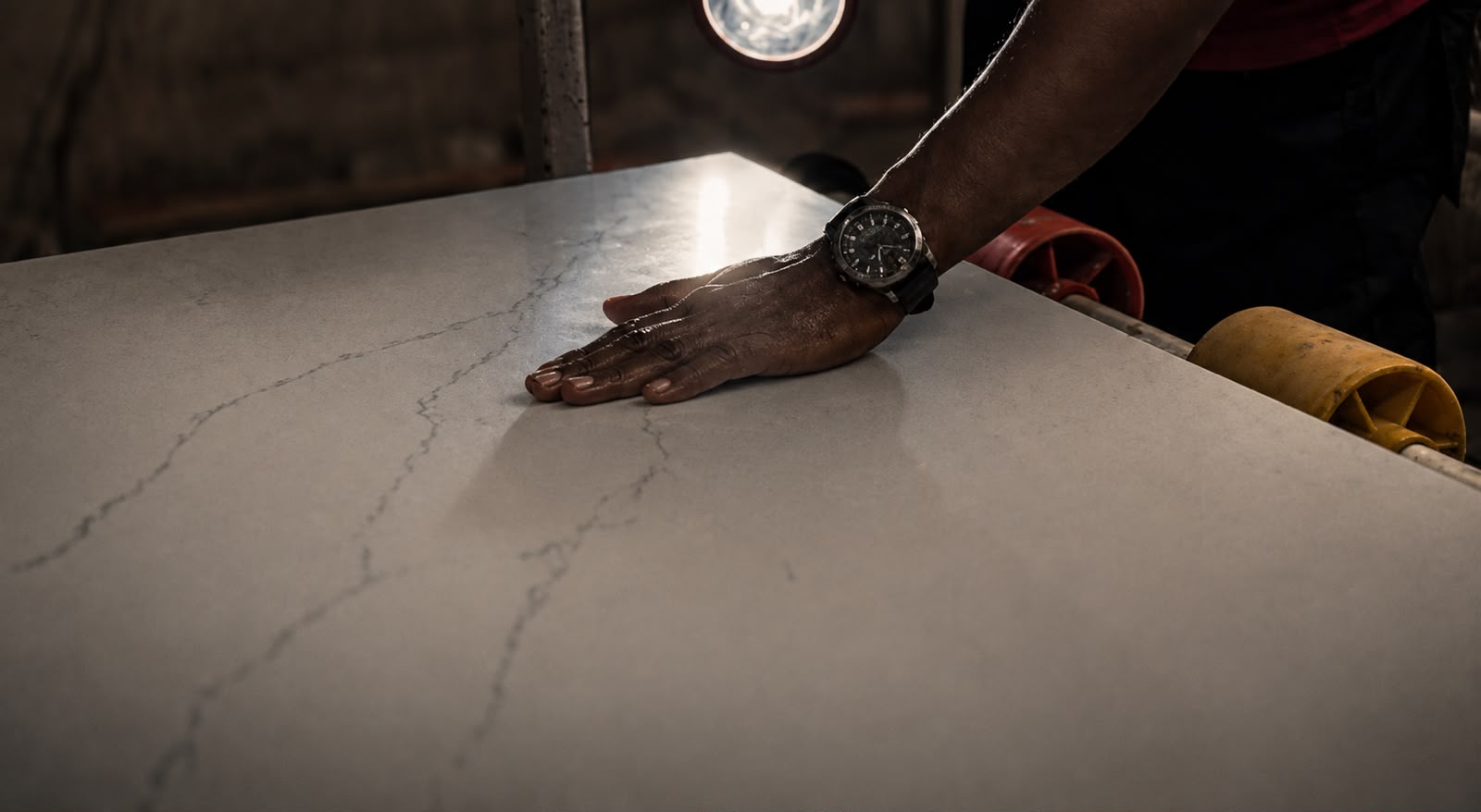 A hand resting on a finished SUNEX engineered quartz slab during quality inspection